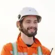 Smiling construction worker wearing an orange safety jacket and helmet